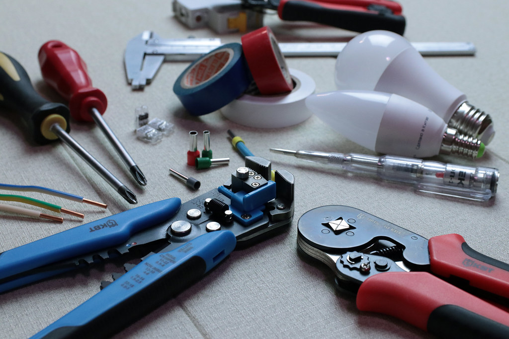 Electrician's wire strippers, crimpers, tape and tester laid out