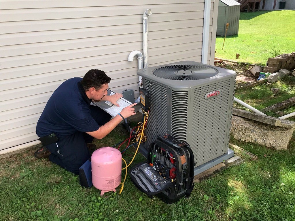 Caddo technician servicing an outdoor AC condenser beside a home